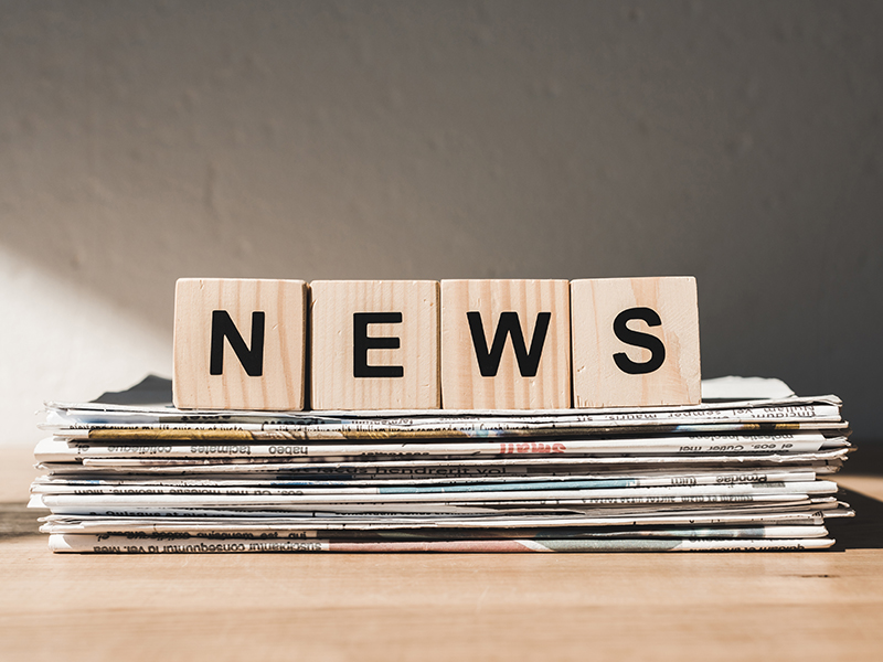 Wooden blocks with news lettering on pile of newspapers